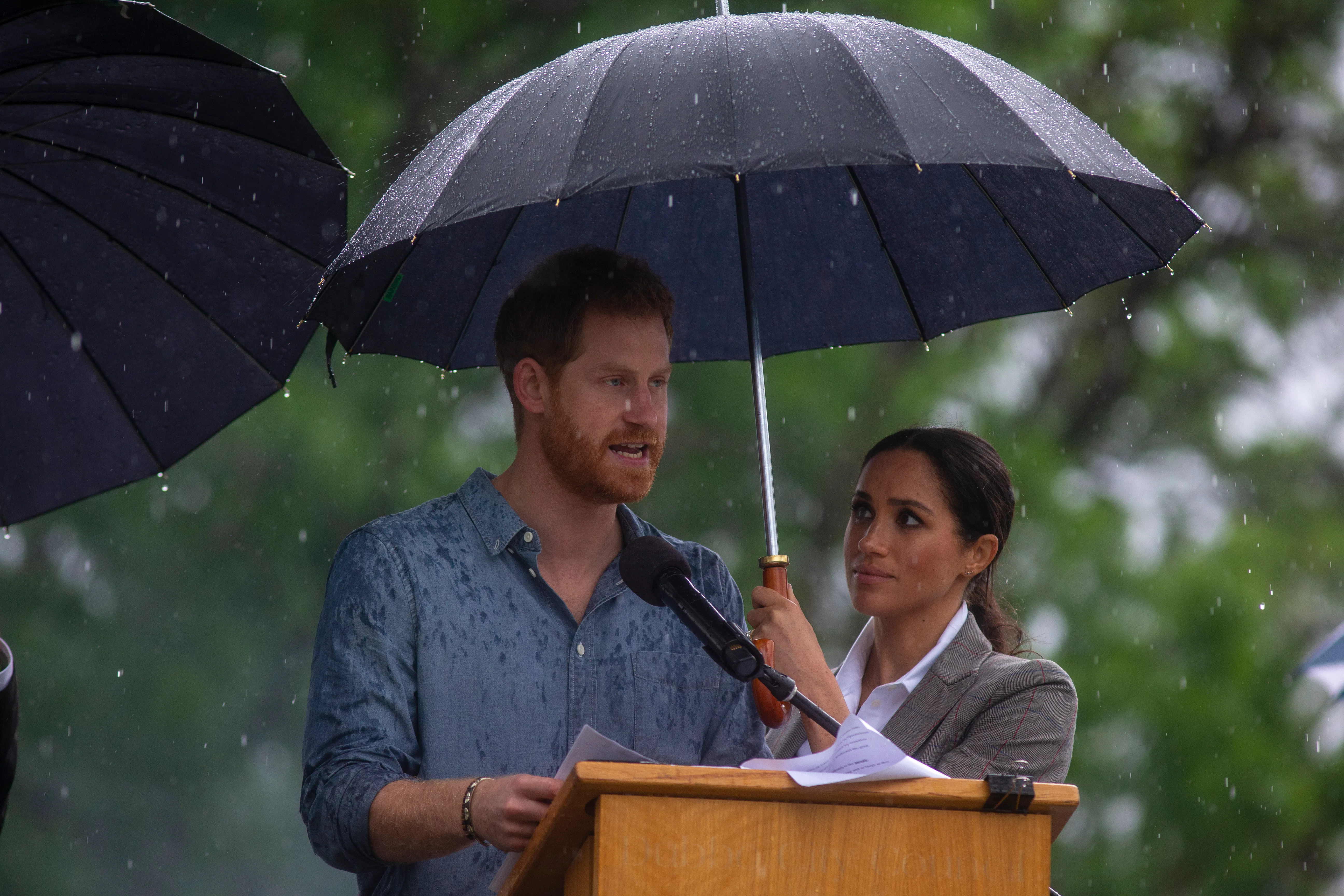 These Photos Of Meghan & Harry Cuddling Under An Umbrella In Australia