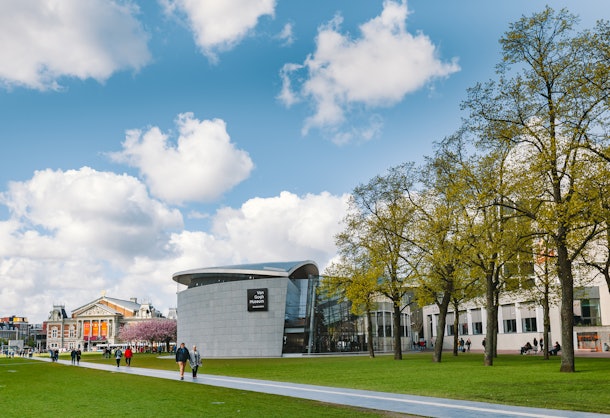 Visitors walk around the Van Gogh Museum in Amsterdam on a cloudy day.