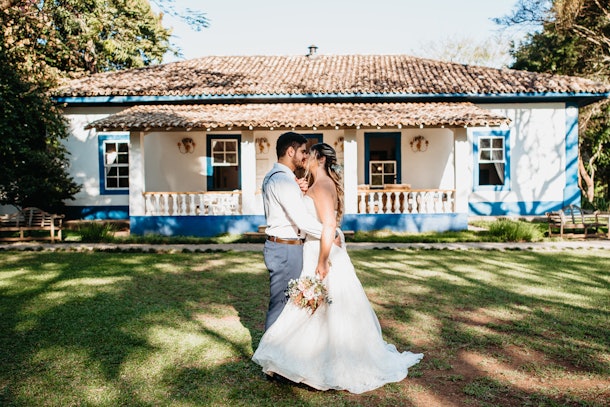 A young couple kisses in the backyard of their beach-like home after getting married.