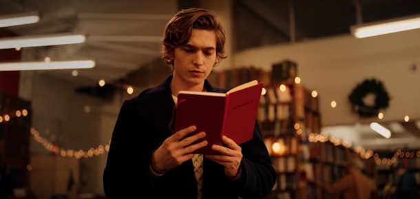 Dash from 'Dash & Lily' looks at a red notebook in the Strand Book Store in New York City. 