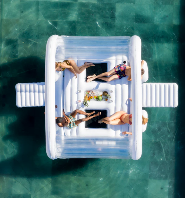 An aerial shot of a group of friends shows them hanging out in a pool on FUNBOY's Giant Dayclub pool float.