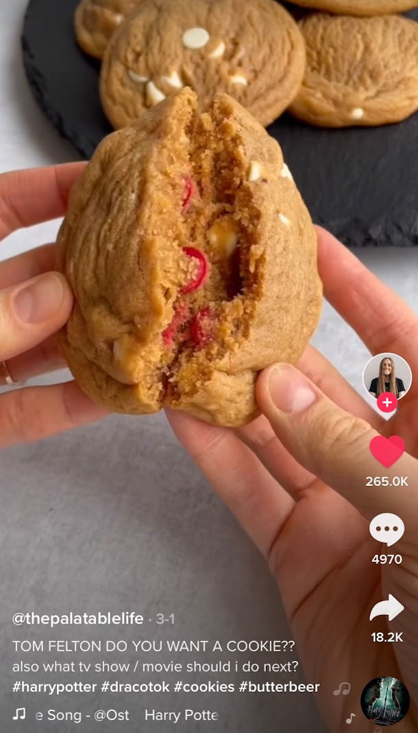 A woman breaks apart a butter beer 'Harry Potter' cookie with red M&M's inside. 