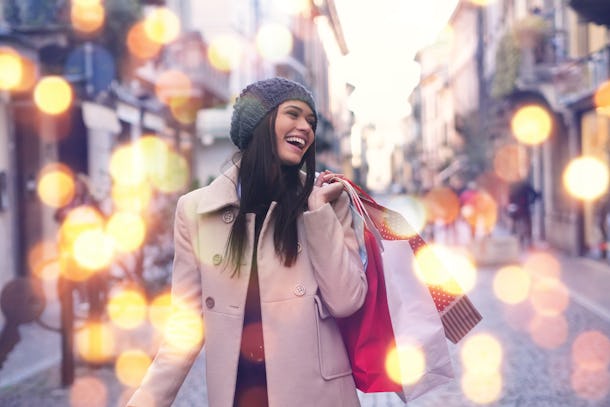 Una niña bonita está sonriendo y feliz comprando en tiendas de la ciudad con rebajas navideñas.  Fantasía: Compras, Vacaciones, Felicidad, Navidad