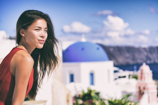Luxury Europe cruise travel vacation Santorini woman looking at view. Tourist Asian girl relaxing at three blue domes, Oia, Greece, european destination.