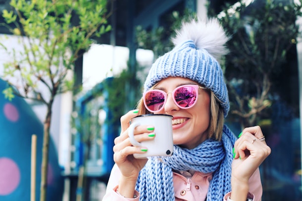 Girl in Winter Clothes in the City Street. Woman in Knitted Sweater, Sunglasses, Beanie and Scarf in the Street