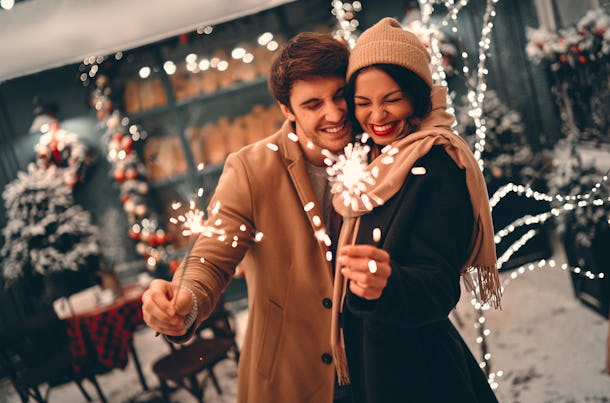 Las parejas románticas jóvenes se divierten con chispas en sus manos en el invierno antes de Navidad.  Disfruten pasando tiempo juntos en la víspera de Año Nuevo.  Los dos amantes se abrazan y se besan en el día de San Valentín