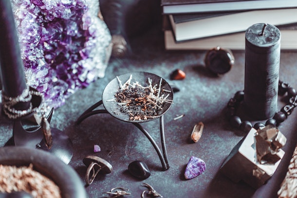 Smoked herbs on a witch's altar for a magical ritual among crystals and black candles.