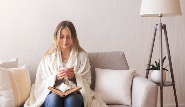 Dreamy girl reading book and enjoying hot coffee at home, panorama, empty space