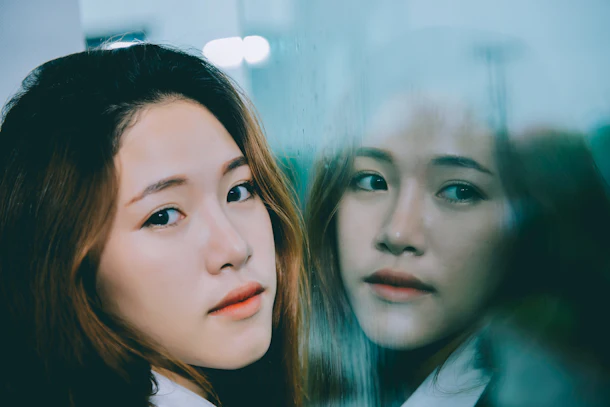 Closeup asian woman sad from love at mirror with reflection in a raining day vintage style,heartbreak woman concept,stress girl