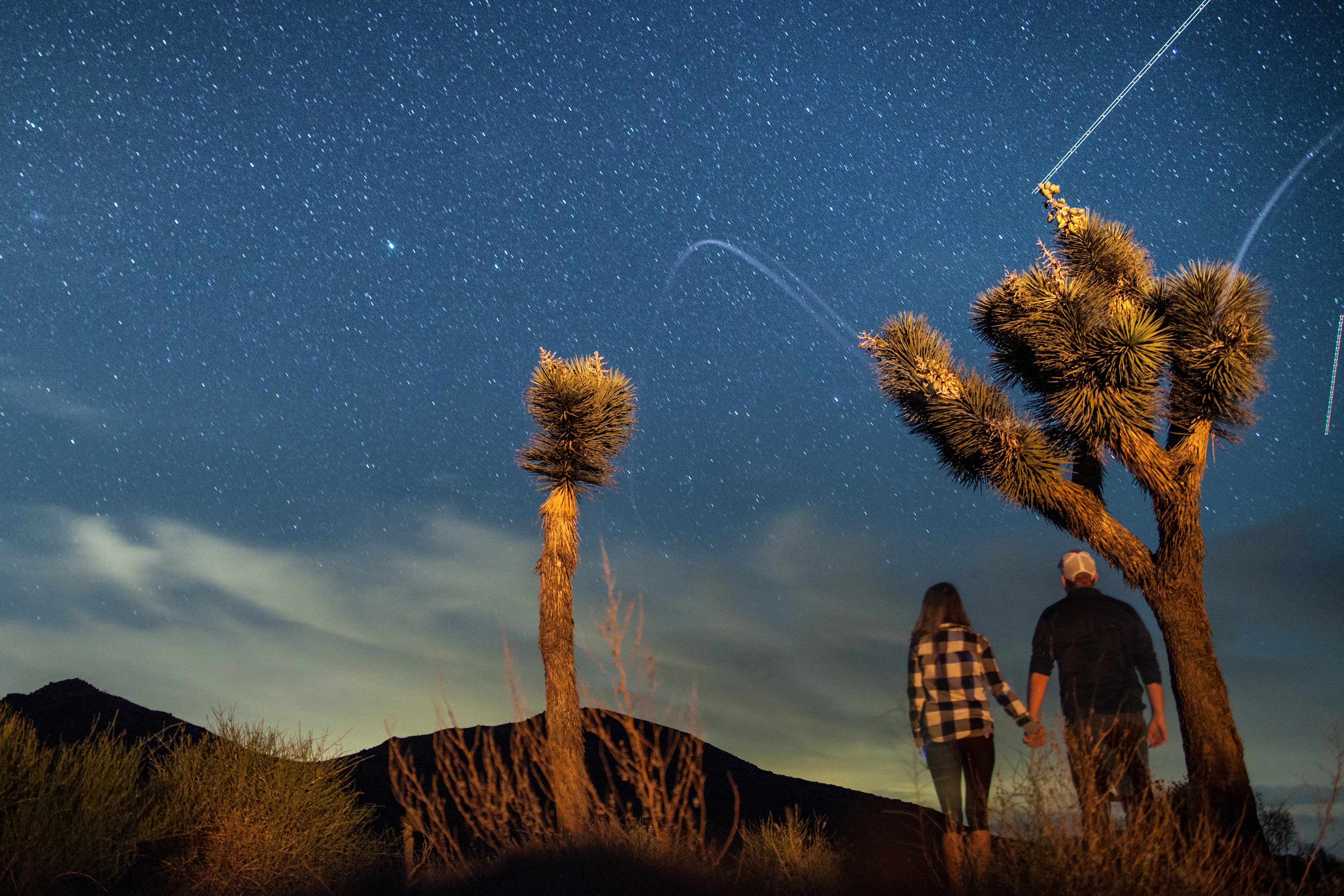 A couple stargazes in Joshua Tree National Park, while holding hands. 